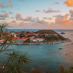 an aerial view of a small town on the ocean with boats in the water at sunset