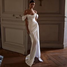 a woman in a white dress posing for the camera with her hand on her hip