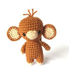 a small crocheted stuffed animal sitting on top of a white surface with one eye open