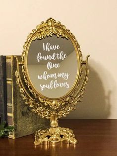 a mirror sitting on top of a wooden table next to a book and potted plant