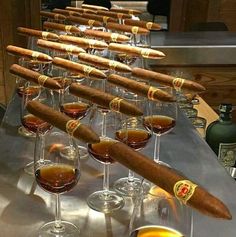 cigars and wine glasses are lined up on a table