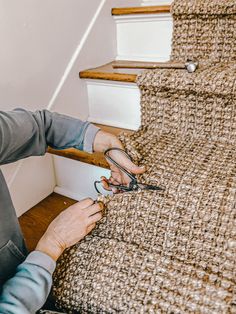 a woman is using scissors to cut up the carpet on the stair treads in her home