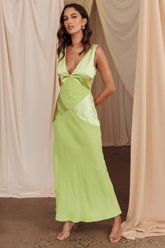 a woman standing in front of curtains wearing a green dress