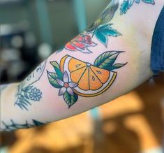 a person with tattoos on their arm holding an orange and flower tattoo design in front of them