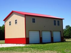 two story garage with red roof and white doors in grassy area next to large field