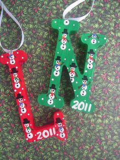 two wooden letters decorated with snowmen and christmas decorations are hanging on a green background