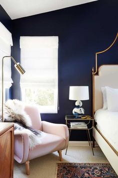 an image of a bedroom with blue walls and white furniture in the room, including a pink chair