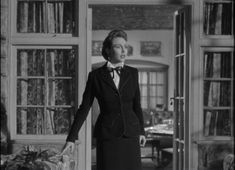 an old photo of a woman in a suit and bow tie standing at the entrance to a library