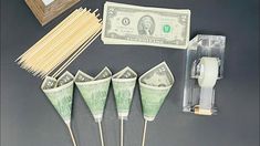 four green toothpicks with money on them next to some matches and other items