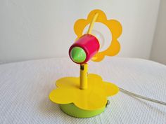 a yellow and green lamp on top of a white tablecloth with a flower design