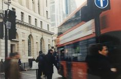 people crossing the street in front of a double decker bus on a busy city street