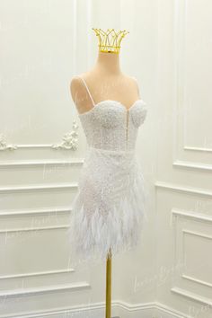 a mannequin wearing a white dress with feathers on it