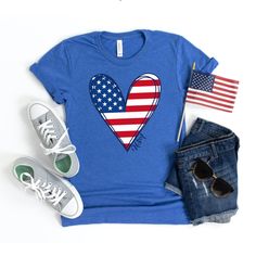 "American Flag Shirt, Women 4th of July Shirt, USA Shirt, July 4th Tshirt, Fourth of July Tee, Merica Shirt, Red White Blue, Memorial Day Tee This cute 4th of July shirt feels soft and lightweight, with the right amount of stretch, and is comfortable and flattering. The design features a cute American flag heart with the word USA along the side. All inks used to print are water-based and eco-friendly. Sizing is UNISEX. It will fit a little more loosely and longer than your typical women's tee (g Memorial Day Blue T-shirt With American Flag Print, Casual Blue T-shirt For Independence Day, Blue Tops With American Flag Print For Memorial Day, Casual Tops With American Flag For Veterans Day, Casual American Flag Tops For Veterans Day, Blue Graphic Tee For Independence Day, Blue Short Sleeve T-shirt For Independence Day, Blue Crew Neck Top For 4th Of July, Patriotic American Flag Relaxed Fit Top