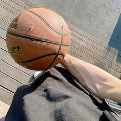 a person sitting down with a basketball on their back and his foot in the air