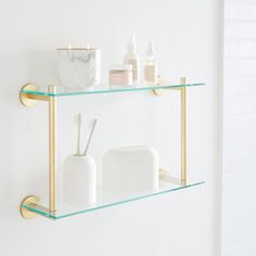 two glass shelves with toothbrushes, soap and lotion on them