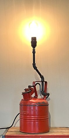 a red can sitting on top of a wooden table next to a light that is turned on