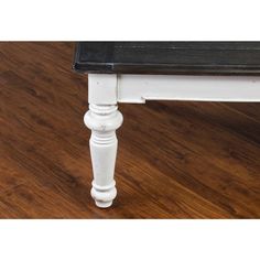 a white bench sitting on top of a wooden floor next to a black and white table