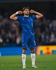 a soccer player is standing on the field with his hands behind his head and looking down