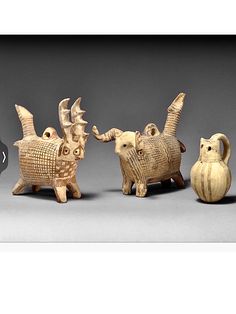 three small ceramic animals standing next to each other on a gray surface with one animal looking at the camera