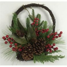 a basket filled with pine cones and red berries sitting on top of a white wall