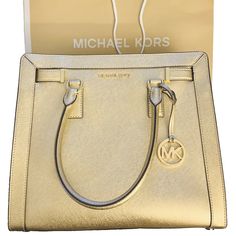 Michael Kors Large Dillion Satchel Crossbody Bag in Gold - The perfect gift comes with MK shopping bag and tags. No dust bag. Saffiano Leather Top Zip closure MK medallion hang charm on the front Gold tone hardware Michael Kors logo in front Flat bottom with protective feet Fully lined with matching MK Sateen Fabric Interior: 4 open pockets; 1 zippered pocket Approx Measurement: H 12” L 13” W 3.5” Dual handles drop 5.5" drop Adjustable/Removable shoulder crossbody strap 21"-25" drop Rectangular Saffiano Leather Bag With Gold-tone Logo Plaque, Classic Gold Satchel With Branded Hardware, Modern Gold Satchel With Branded Hardware, Designer Gold Satchel, Gold Travel Satchel With Branded Hardware, Luxury Michael Kors Bags In Saffiano Leather, Classic Gold Satchel For Shopping, Modern Michael Kors Saffiano Leather Bag, Michael Kors Gold Travel Satchel