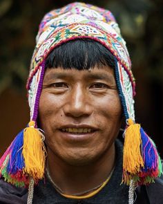 a man wearing a colorful hat with tassels on his head