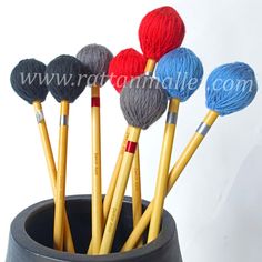 several balls of yarn and crochet hooks in a cup with pencils inside