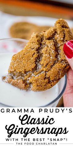 a close up of a person holding a cookie in front of a glass of milk