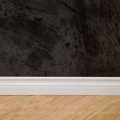 an empty room with wood flooring and black marble wallpaper on the walls behind it