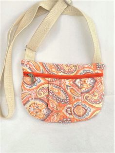 "Peachy Paisley Print Small Zip Purse. Cross Body Quilted Mini Purse, , Hands Free Pouch, Travel Cross Body Purse, Quilted Zipper Phone Pouch has soft pleats on the front. This hip pouch opens with a zipper across the front and has an inside pocket.  It's click buckle adjustable cotton web strapping that will fit most average size waists.   It can be used as a hands free travel purse or cell phone pouch.  Great for outfits that have no pockets.  Handy hands free pouch for shopping, dog walking, hiking, cycling, etc. It is handmade of fully quilted exterior and lining.  It can be hand washed and laid out flat to dry.   Your size should be in the middle range to provide for comfort adjusting.  Easily put on and off with a click buckle.    Overview:   *  Size: 9\" across the top and 7\" tall Cheap Pouch With Adjustable Strap, Cheap Everyday Use Pouch With Wrist Strap, Cheap Pouch With Wrist Strap, Cheap Rectangular Pouch With Wrist Strap, Affordable Pouch Bag With Functional Pockets, Cheap Pouch Bag With Flat Pocket, Cheap Festival Bags With Zipper Pocket, Cheap Orange Bag With Zipper Pouch, Cheap Crossbody Pouch With Removable Section