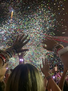 confetti being thrown in the air at a concert with people holding their hands up