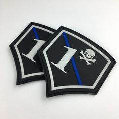 two black and white patches with blue lines on them, one has a skull and the other has a crossbone