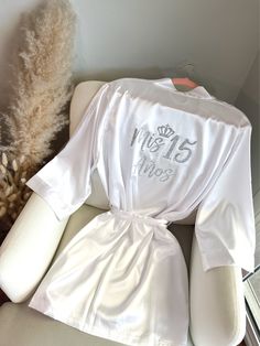 "Get ready for your Mis Quince Años celebration in style with our Quinceañera Satin Robes!  Crafted from soft and silky high-quality satin, these robes are designed to make you feel like a princess on your special day. With different options for text color and designs on the back side, you can customize your robe to match your unique style and personality. Not only are these robes perfect for getting ready, but they're also ideal for Instagram and Pinterest photos. Order yours Mis Quince robe to Personalized Quince Robe, Champagne Quince Robe, White Quince Decorations, 15 Ideas Quinceanera Decorations, Quince Robe Ideas, Mis Quince Robe, Quince Things You Need, 15th Quinceanera Quince Ideas, Destination Quinceanera