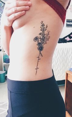 a woman's lower back tattoo with flowers on her left side ribcage