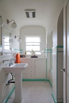 a white bathroom with green trim on the walls and floor, along with two sinks