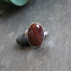 Plume agates are thought to eliminate and transform negativity...Who knew? It is also just a really pretty earthy gemstone...found in Oregon, cut in Oregon and made in Oregon! Here are the details:This ring has an oval red agate ring that is made with a locally-sourced & cut cabochon and set in fine & sterling silver on a sturdy silver band. This ring was handmade by Will Macy in Corvallis, OR. Size 11 1/4 Artisan Agate Oval Ring, Brown Oval Agate Rings, Oval Agate Ring With Large Stone, Oval Brown Agate Rings, Oval Agate Rings For Healing, Brown Oval Rings With Natural Stones, Oval Brown Rings With Natural Stones, Oval Brown Ring With Natural Stones, Plain Silver Rings