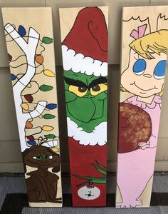 three wooden skis with cartoon characters painted on them, one in santa's hat and the other in snowboarding gear