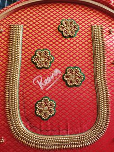 a red purse with gold trimmings and some green flowers on it's side