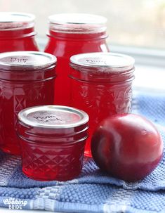 red jars with lids and an apple on a blue towel