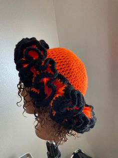 an orange and black crocheted hat on top of a mannequin head