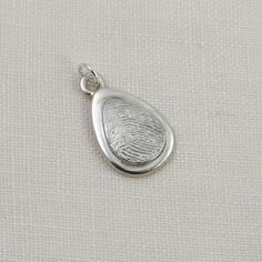 Keep your loved one with you always, with this lovely fingerprint teardrop pendant that combines elegance and sentimentality. Handcrafted in solid sterling silver, this pendant features a sleek silver oval layered with a smaller oval fingerprint, creating a unique and personalized accessory. The raised fingerprint accentuates its importance and draws attention to the beautiful details of the print. The smooth edges and shiny finish of the pendant give it a sophisticated touch, making it suitable Fingerprint Pendant, Thumb Print, Thumb Prints, Fingerprint Jewelry, Keepsake Jewelry, Smooth Edges, Teardrop Pendant, Memorial Keepsakes, Small Heart