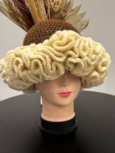 a mannequin's head wearing a crocheted hat with feathers