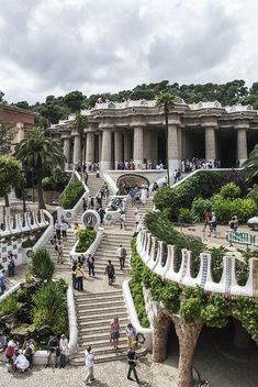 many people are walking up and down the stairs in front of a building with columns