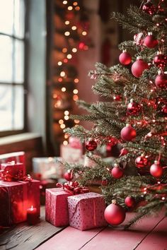 a christmas tree with presents under it on a wooden floor in front of a window