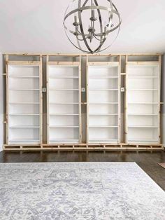 an empty room with white bookcases and a chandelier