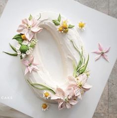 a cake decorated with flowers and greenery on top of a white plate, ready to be cut