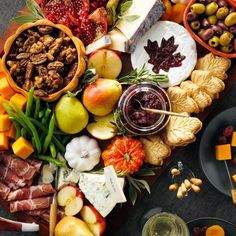 an assortment of cheeses, fruits and meats are arranged on a platter