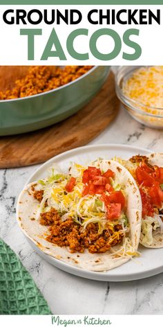 two tacos on a plate with ground chicken in the background and other food items