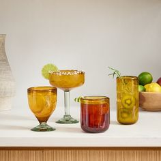 three glasses and two vases sitting on a counter