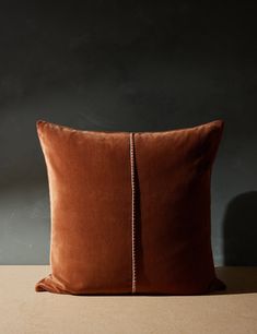 a brown pillow on a table with a black wall in the backgrounnd